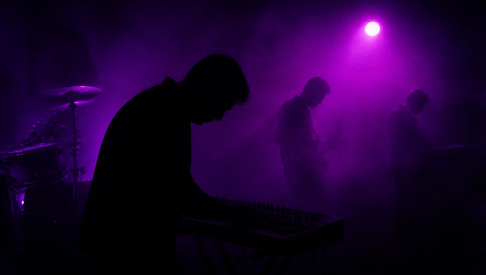 Dalnak on stage, three silhouettes in purple fog